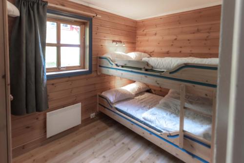 two bunk beds in a wooden room with a window at Bakkebyvegen 1D in Trysil