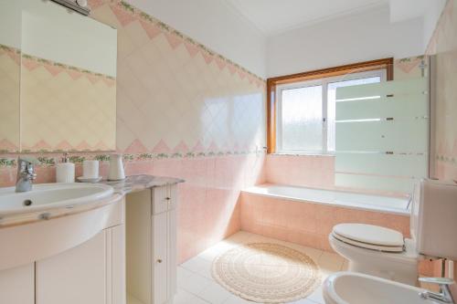 een badkamer met een wastafel, een toilet en een bad bij Private Gardened House - 5min from the beach in Viana do Castelo