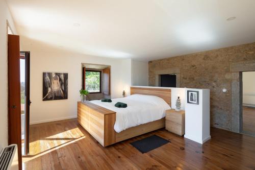 a bedroom with a large bed and a brick wall at Portugal Active Armadas Lodge in Caminha