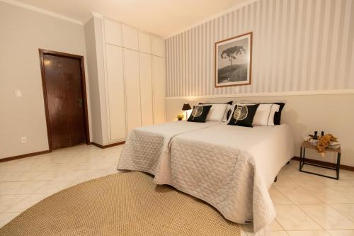 a bedroom with a large white bed with pillows at Hospedaria do Lago in Espirito Santo Do Pinhal