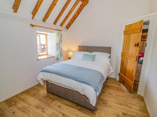 a bedroom with a bed and a wooden floor at Munderfield Mill in Bromyard