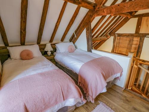 two beds in a attic room with wooden beams at Munderfield Mill in Bromyard