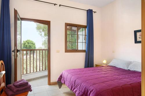 1 dormitorio con cama morada y balcón en Holiday Cottage Santa Lucía 2 en Santa Lucía