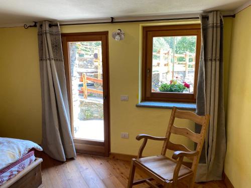 Un dormitorio con una cama y una silla y una ventana. en Maison Bosc, Champorcher, en Champorcher