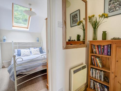 ein Schlafzimmer mit einem Bett und einem Bücherregal mit Büchern in der Unterkunft 52 Fernhill Heights in Bridport