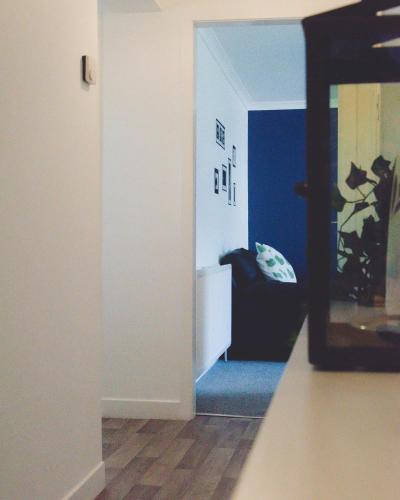 a hallway with a mirror and a room with blue walls at Dumfries Apartment in Dumfries
