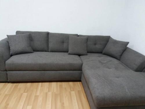 a grey couch in a living room with a wooden floor at The Green House - Apuseni Mountains in Pietroasa