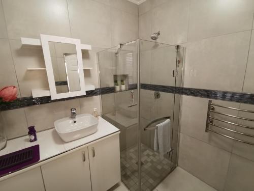 a bathroom with a glass shower and a sink at Protea Suite in Bellville