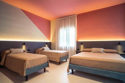 2 Betten in einem Zimmer mit orangefarbenen und violetten Wänden in der Unterkunft La Maison - Boutique Rooms in Sperlonga