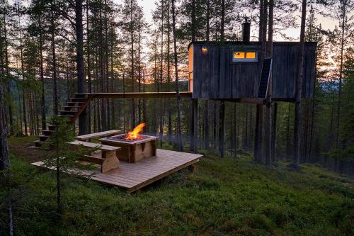 a tree house with a fire pit in a forest at Swedish Treehouse 