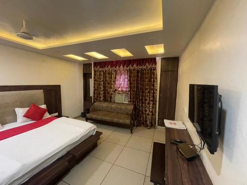ein Schlafzimmer mit einem Bett, einem Sofa und einem TV in der Unterkunft Hotel Himgiri in Jammu
