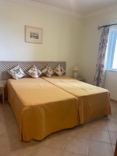 a bedroom with a large bed with yellow sheets and pillows at Lovely 2 Bedroom Home inside a Resort in Albufeira in Albufeira