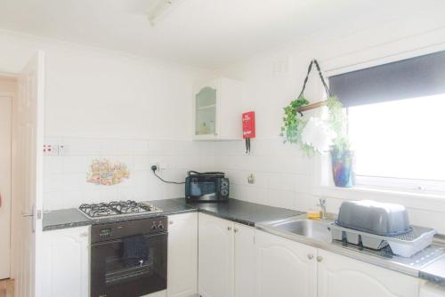 uma cozinha com um lavatório e um fogão forno superior em Dumfries Apartment em Dumfries