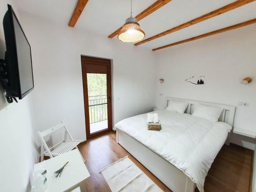 biała sypialnia z łóżkiem i telewizorem w obiekcie Domeniul Acasa in Vadu Izei Maramu w mieście Vadu Izei