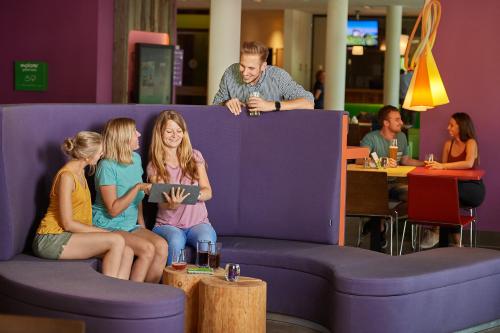 a group of people sitting on a purple couch at Explorer Hotel Garmisch in Farchant