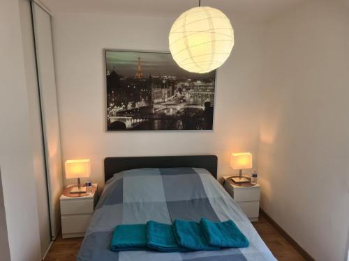 a bedroom with a bed with two lamps and a picture at Appartement avec rez de jardin à Disneyland in Montévrain