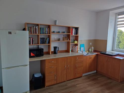 a kitchen with a white refrigerator and wooden cabinets at Gościniec Biebrzański in Lipsk