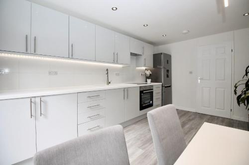 a kitchen with white cabinets and a table and chairs at Katie's house in Cumbernauld