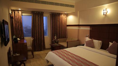 a hotel room with a bed and a living room at Rain Drops Hotel in Chennai