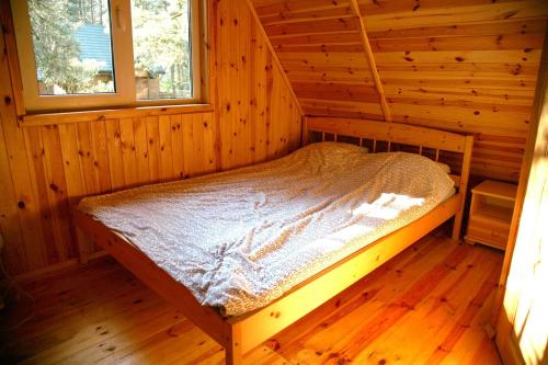 a bed in a wooden room in a cabin at Domki-Mazury in Pasym