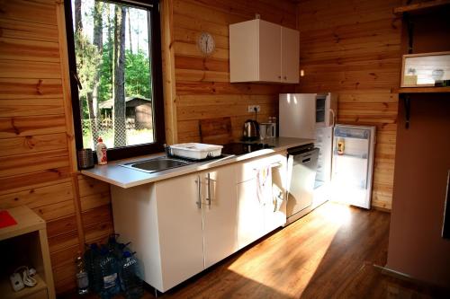 a kitchen with white cabinets and a window in a cabin at Domki-Mazury in Pasym