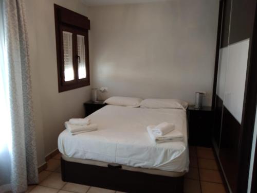 1 dormitorio con 1 cama con sábanas blancas y toallas en Aracena Maravillas, en Aracena