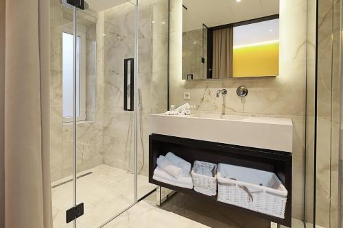 een badkamer met een douche, een wastafel en een spiegel bij Maccani Black Luxury Suites in Belgrado