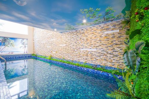 a swimming pool in a room with a brick wall at Golden Star Hotel & Apartment by THG in Da Nang