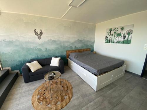 1 dormitorio con cama, sofá y mesa en Le Panorama - GÎTES MARCK, en Turckheim