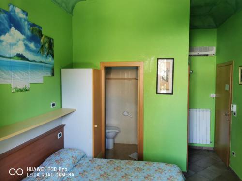 a green bedroom with a bed and a toilet at Porto Recanati Zimmer in Porto Recanati