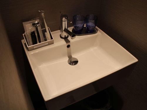 a bathroom sink with a faucet and cups on it at Hotel Halrotto Fukuoka Hakata in Fukuoka