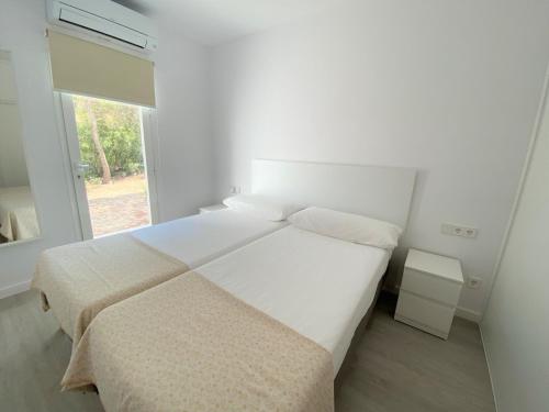 a white bedroom with a large bed and a window at Can Valonsadero, Villa con Piscina in Es Calo