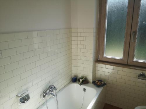ein weiß gefliestes Bad mit einer Badewanne und einem Fenster in der Unterkunft Villa Florida in Fiuggi