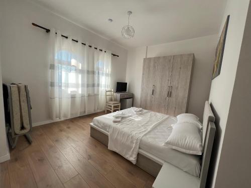 a white bedroom with a bed and a desk at Bujtina Celiku in Burrel
