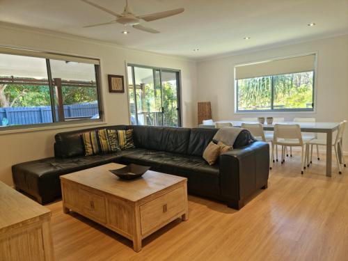 a living room with a black leather couch and a table at At Melaleuca 3 in Point Lookout