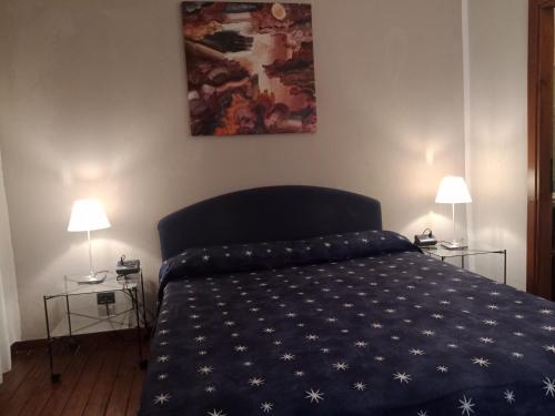 a bedroom with a bed with a blue comforter and two lamps at Locanda del Glicine in Campagnatico