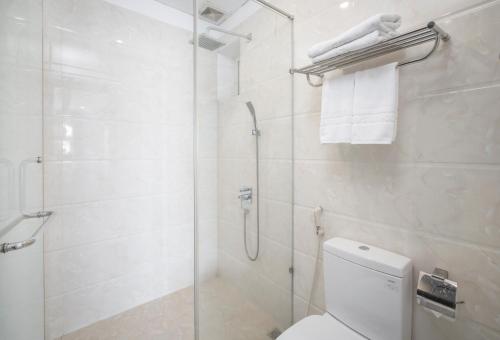 a white bathroom with a shower and a toilet at Golden Star Hotel & Apartment by THG in Da Nang