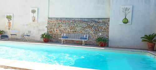 a blue swimming pool with a bench next to a wall at Lacanepière in Générac
