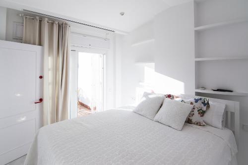 une chambre blanche avec un lit blanc et une fenêtre dans l'établissement Ático con terraza Centro Ciudad, à El Puerto de Santa María