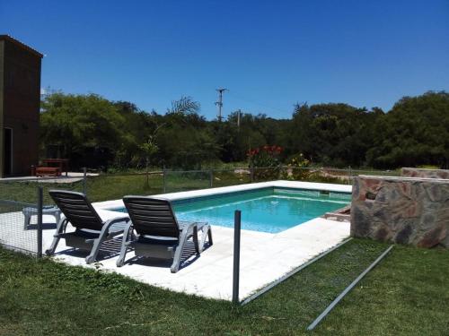 una piscina con 2 sillas y una mesa en Cabañas Ismiango "Agua de los pajaritos" en Collagasta