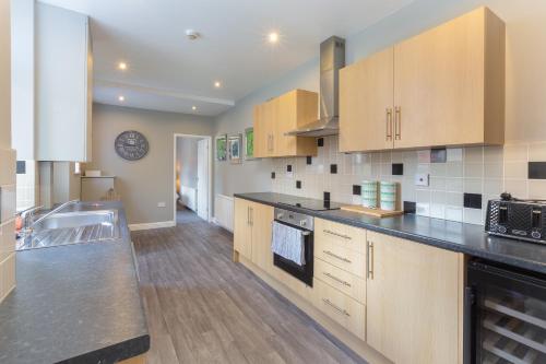 a kitchen with wooden cabinets and a black counter top at Ashton Mews apartment with free parking in Saint Annes on the Sea