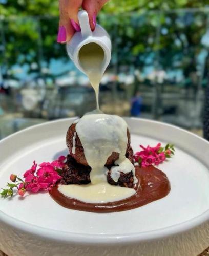 a person drizzling sauce onto a dessert on a plate at Hotel Espadarte in Iriri