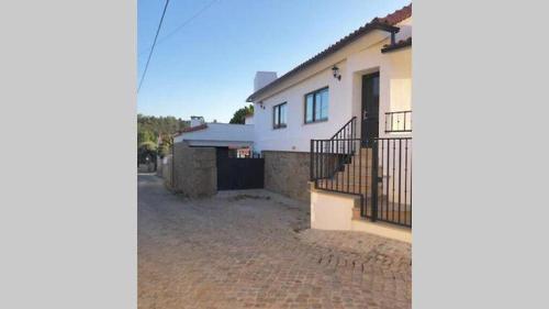 a white house with a black gate and a driveway at Grandfather's House in Tábua