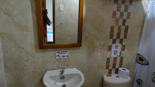 a bathroom with a sink and a mirror and a toilet at Hotel Casa Finca La Maracuya in Ríohacha