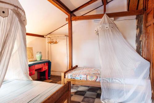 a bedroom with two beds with mosquito nets at Unique Balian beach house in Antasari