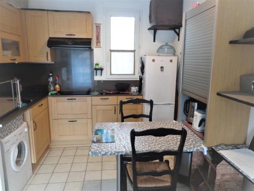 uma cozinha com uma mesa e um frigorífico branco em T2 Anasa em Digne-Les-Bains