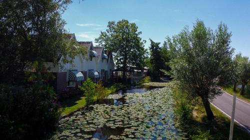a river with rocks and trees next to a house at Hotel Zuideinde in Nieuwkoop