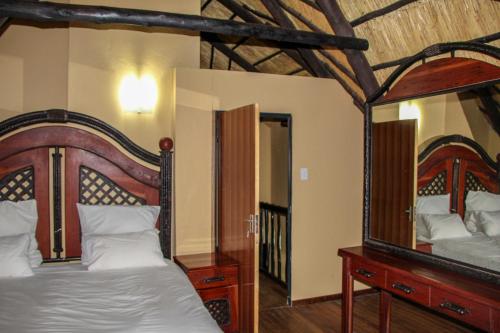 a bedroom with a canopy bed and a mirror at Mapelepele Cottage in Simunye