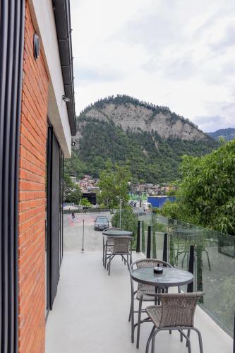 a patio with tables and chairs and a mountain at Borjomi Bridge Hotel in Borjomi