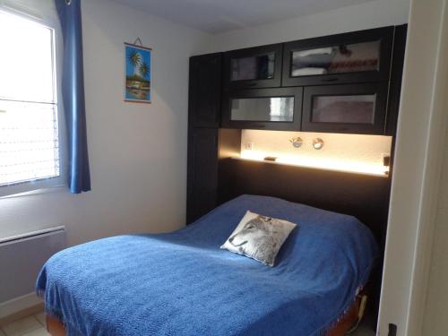 um quarto com uma cama com um cobertor azul em T2 Anasa em Digne-Les-Bains